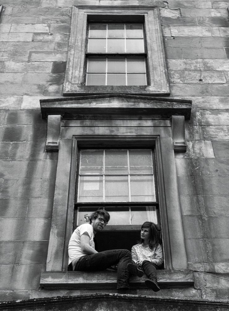 View of a couple sitting at their windowsill in Garnethill of a Sunday
